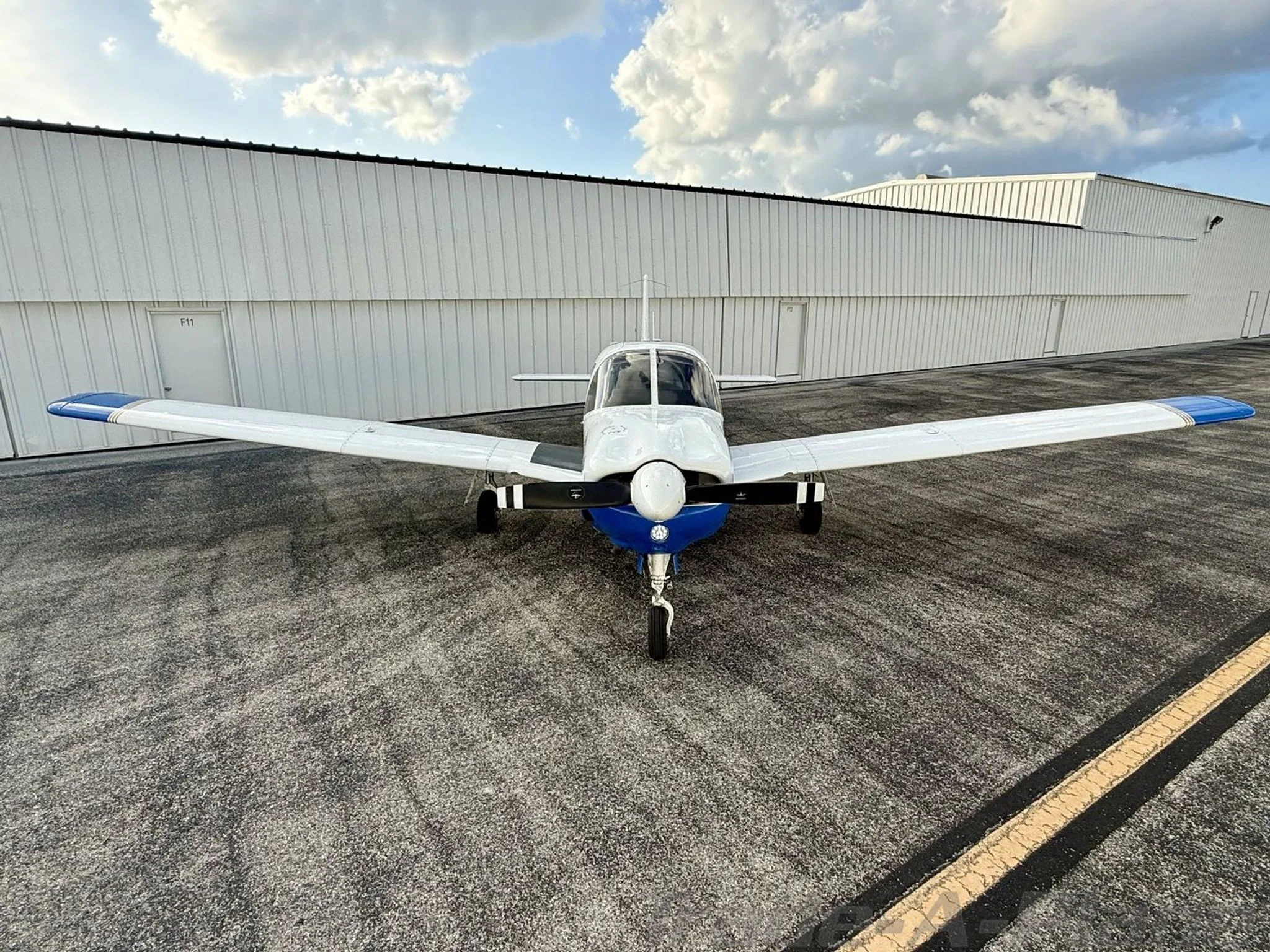 A front view of the white and blue Piper Arrow aircraft (N338PA) parked on the tarmac.