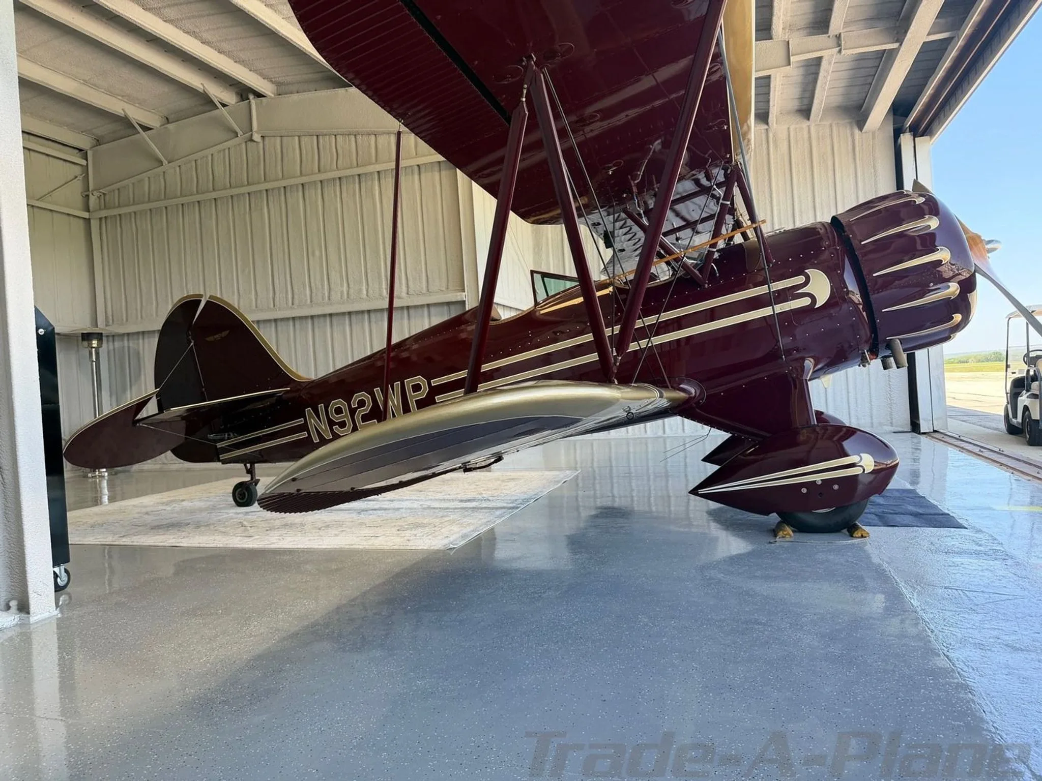 A WACO YMF-5C positioned inside a hangar.