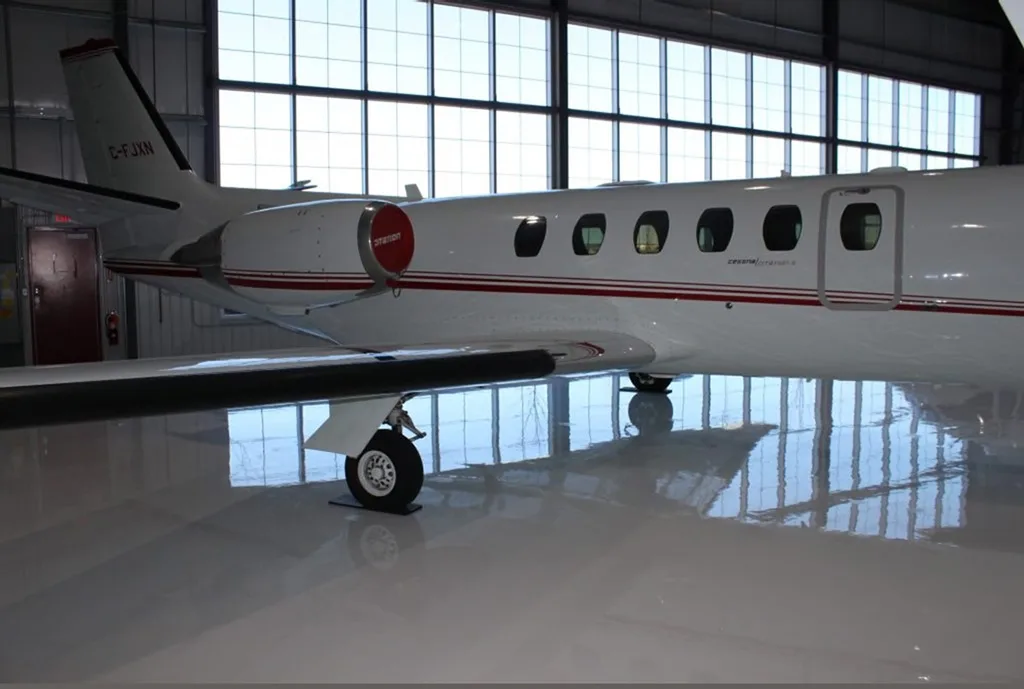A close-up view of the rear fuselage and engine of a white Cessna Citation aircraft in a hangar.