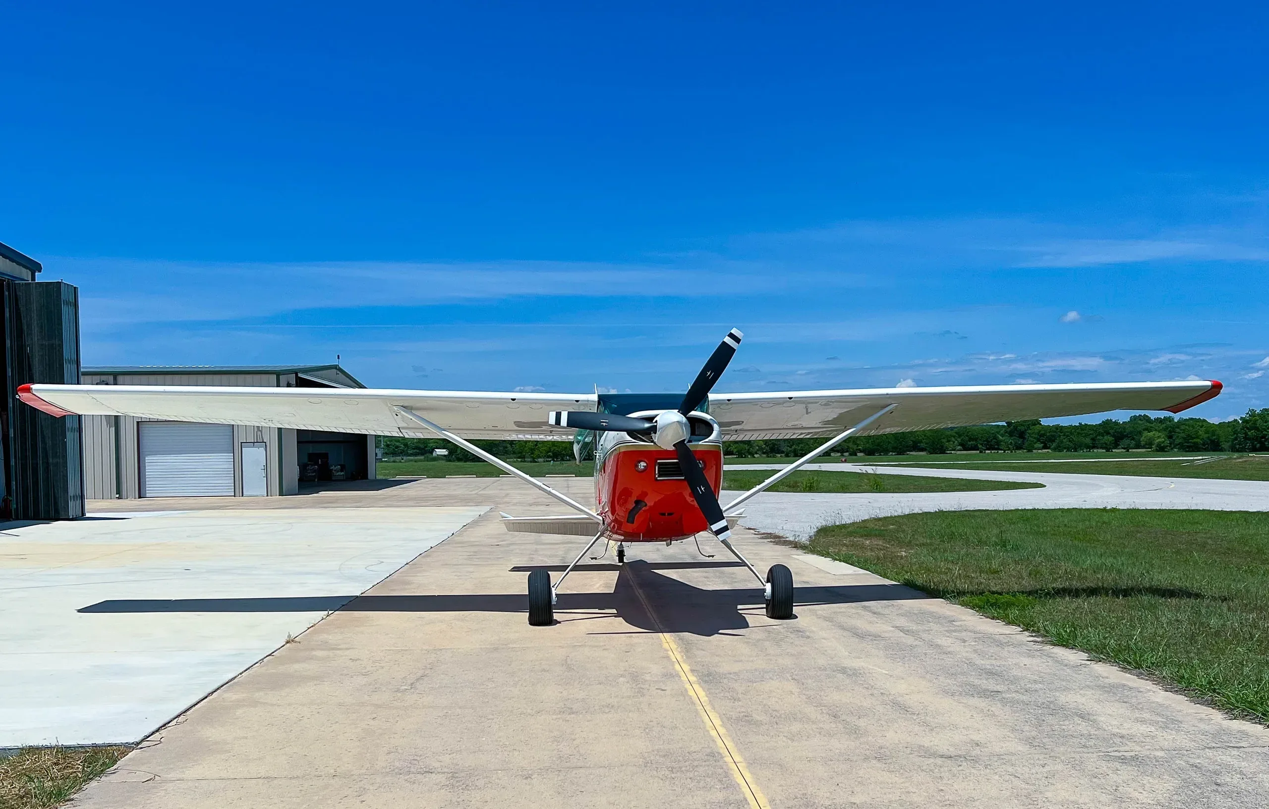Front view of the Cessna 185 aircraft with a red and white paint scheme parked on the tarmac.