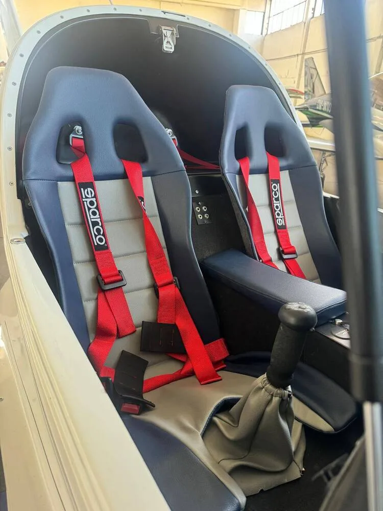The interior of a Freccia aircraft showing two blue and grey Sparco racing seats with red harnesses.