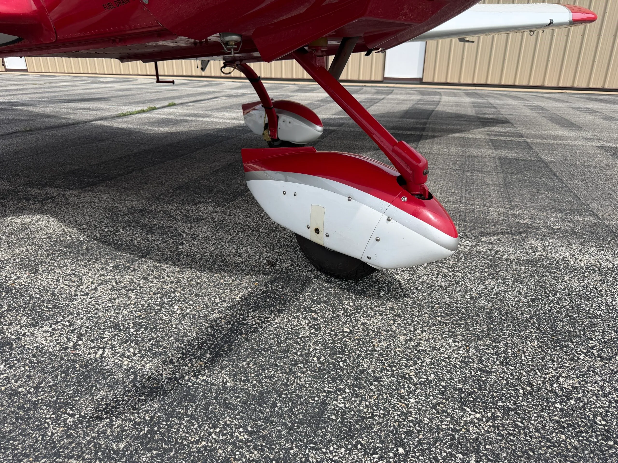 Close-up view of the red and white main landing gear of the SportCruiser aircraft on the tarmac.