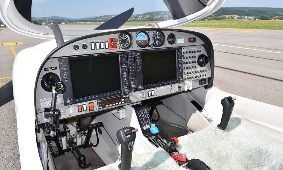 The cockpit of a Diamond DA40 aircraft, showing the instrument panel with two large display screens and controls.