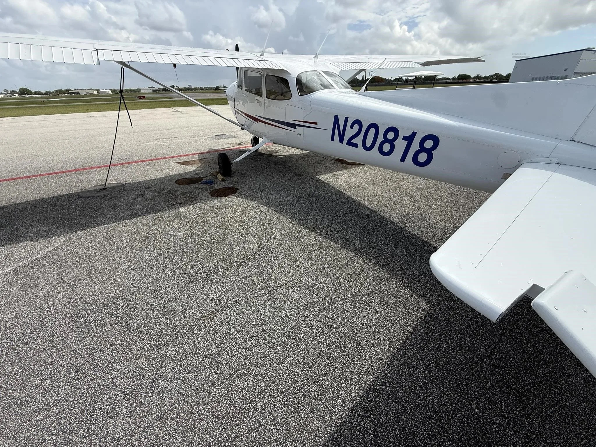 A side view of the white Cessna 172 (N20818) showing the registration and red and blue stripe.