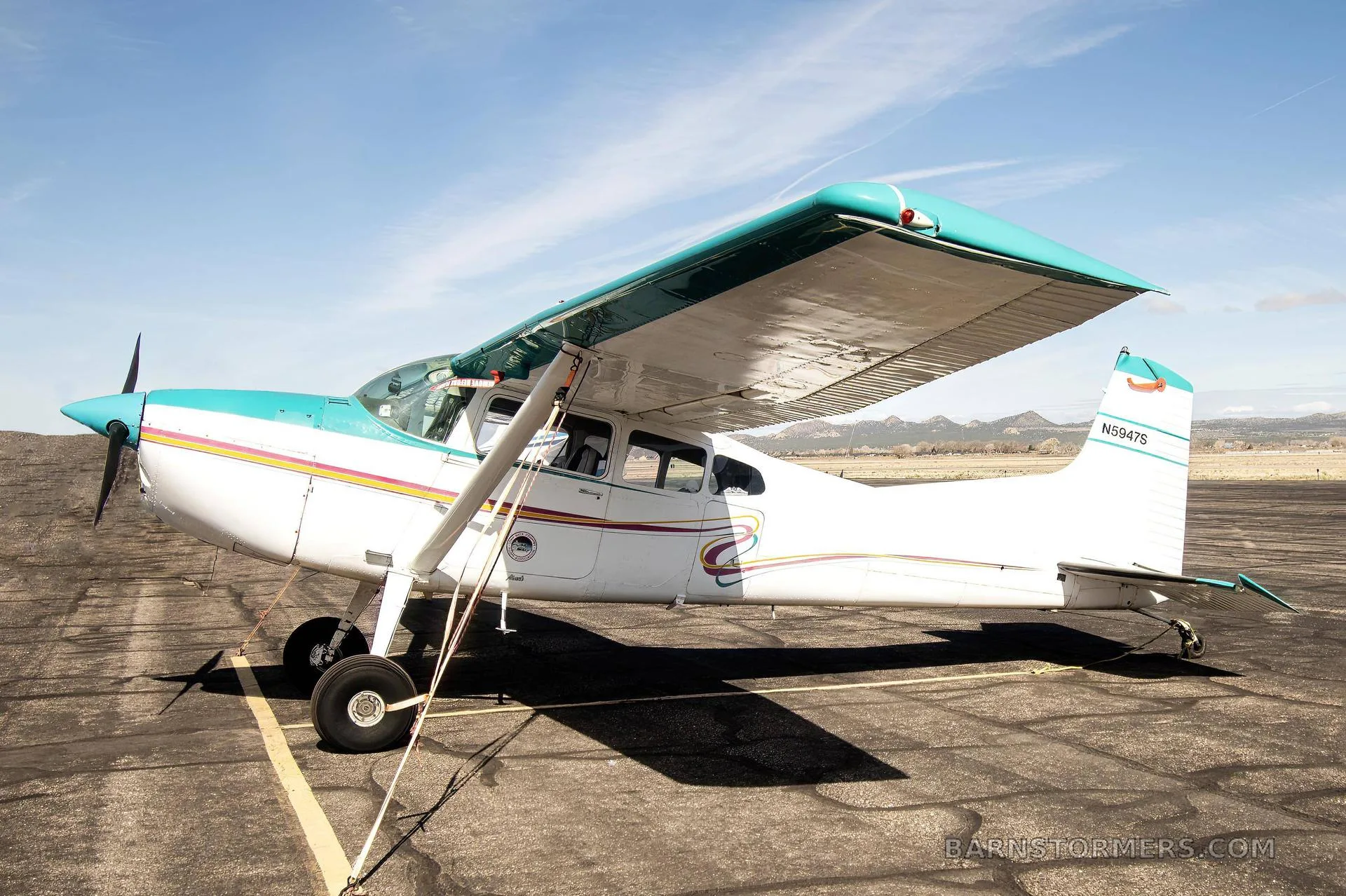 Side view of a white and teal single-engine propeller aircraft with registration N5947S parked on an airfield.