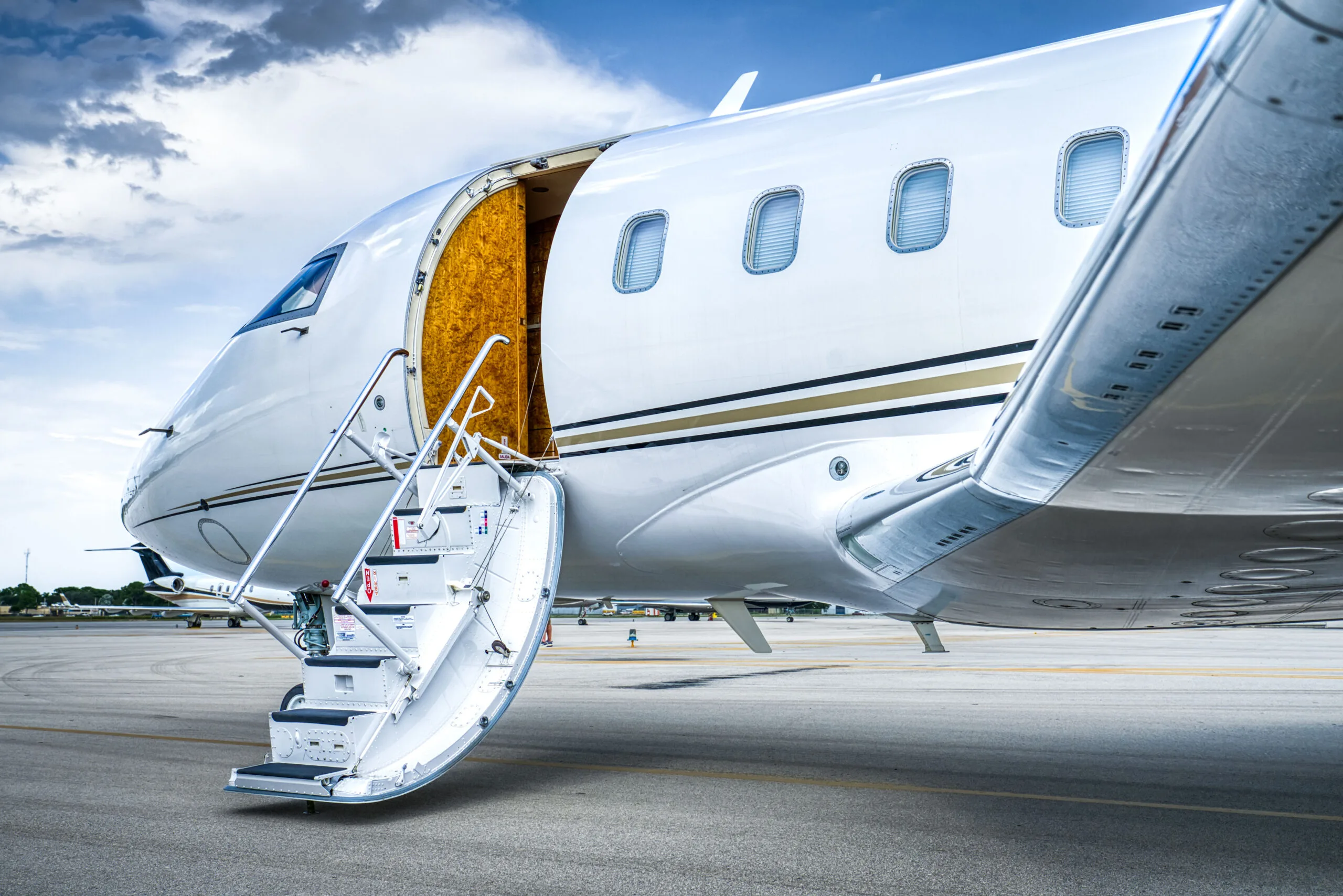 A close-up of the open main cabin door and extended airstairs of a white Bombardier Challenger business jet.