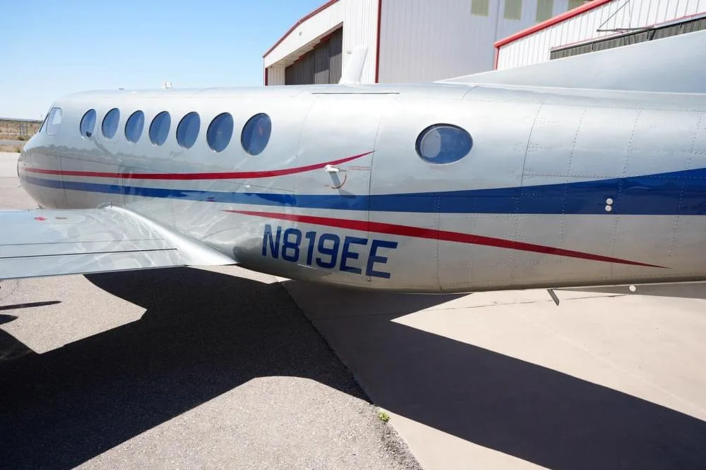A close-up of the fuselage of the silver and blue aircraft N819EE, showing the registration and windows.