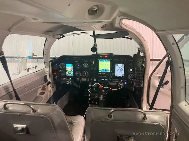 A wider view of the aircraft cockpit, showing the instrument panel, controls, and the front two seats.
