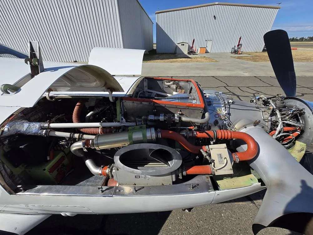 The engine compartment of a Piper Meridian aircraft with the cowling open, revealing the turbine engine and internal components.