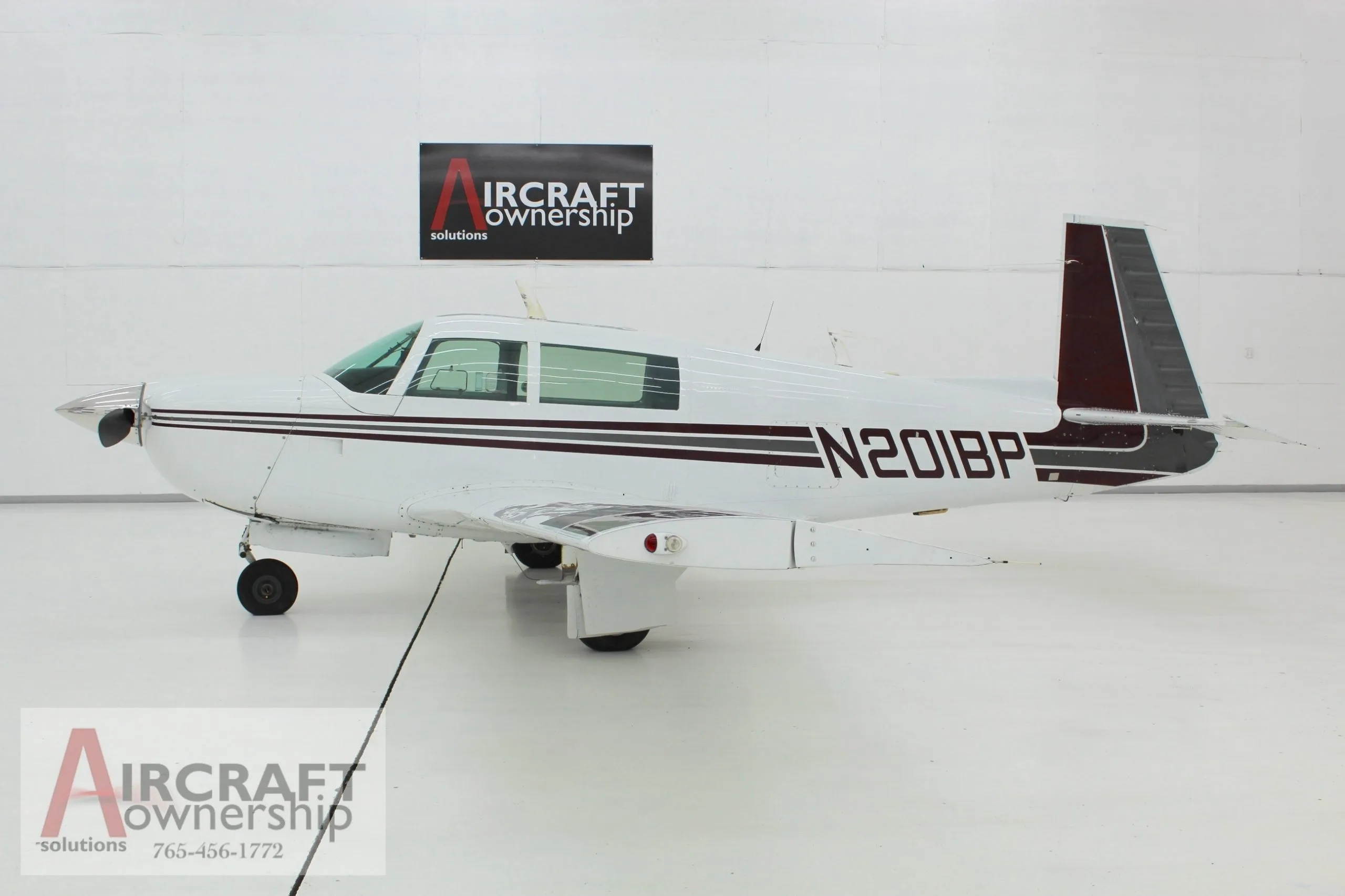 Side view of the white and brown N201BP aircraft in a hangar.