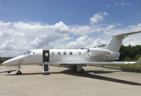 A Phenom 300E aircraft is parked on the tarmac with the boarding stairs down.