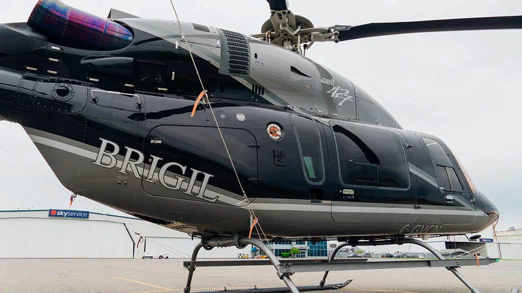 A close-up side view of the black and silver Bell 427 helicopter, showing "BRIGIL" branding and registration C-GVCN.