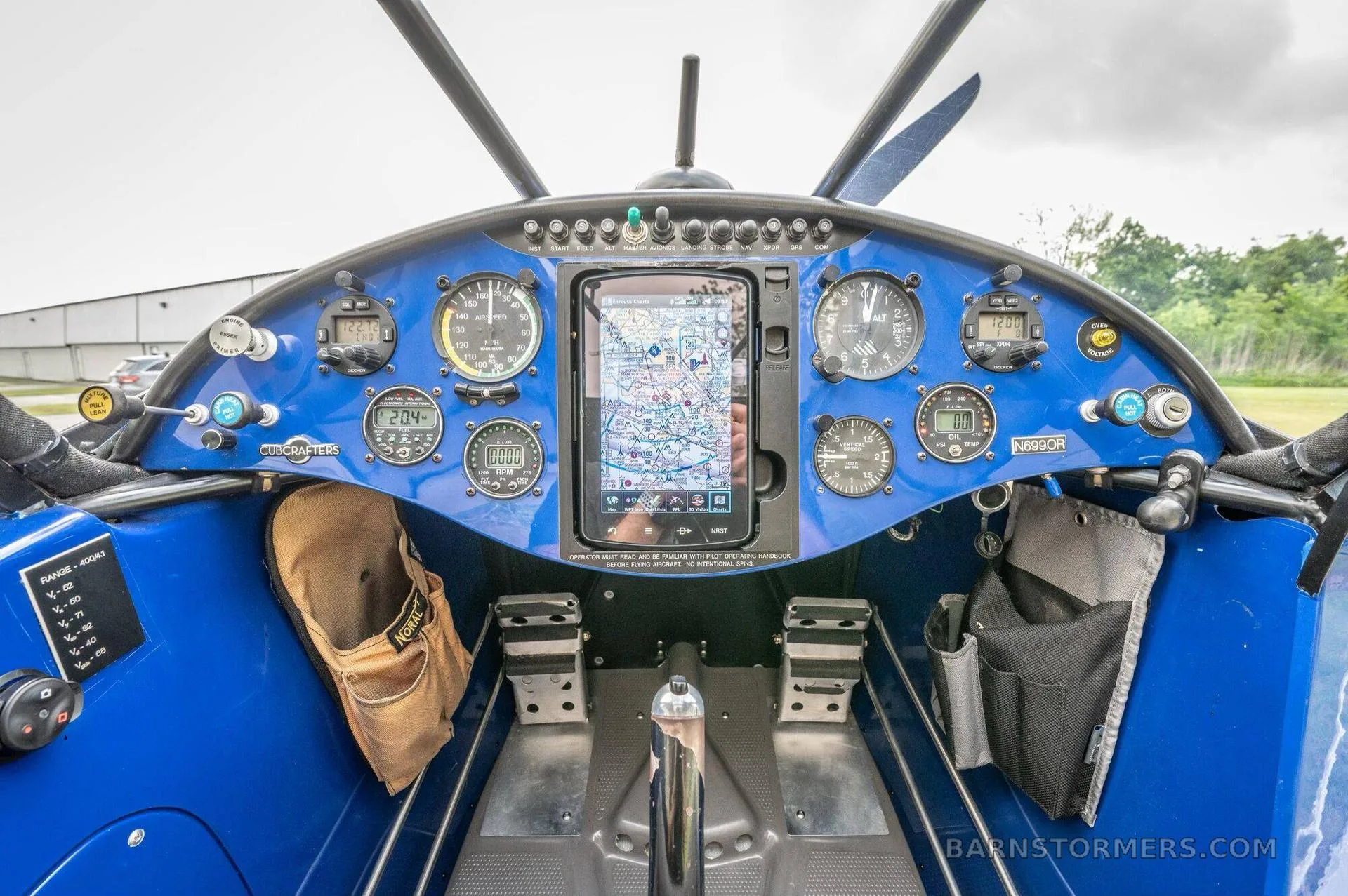 The blue cockpit of a light aircraft features a central tablet display and analog gauges.