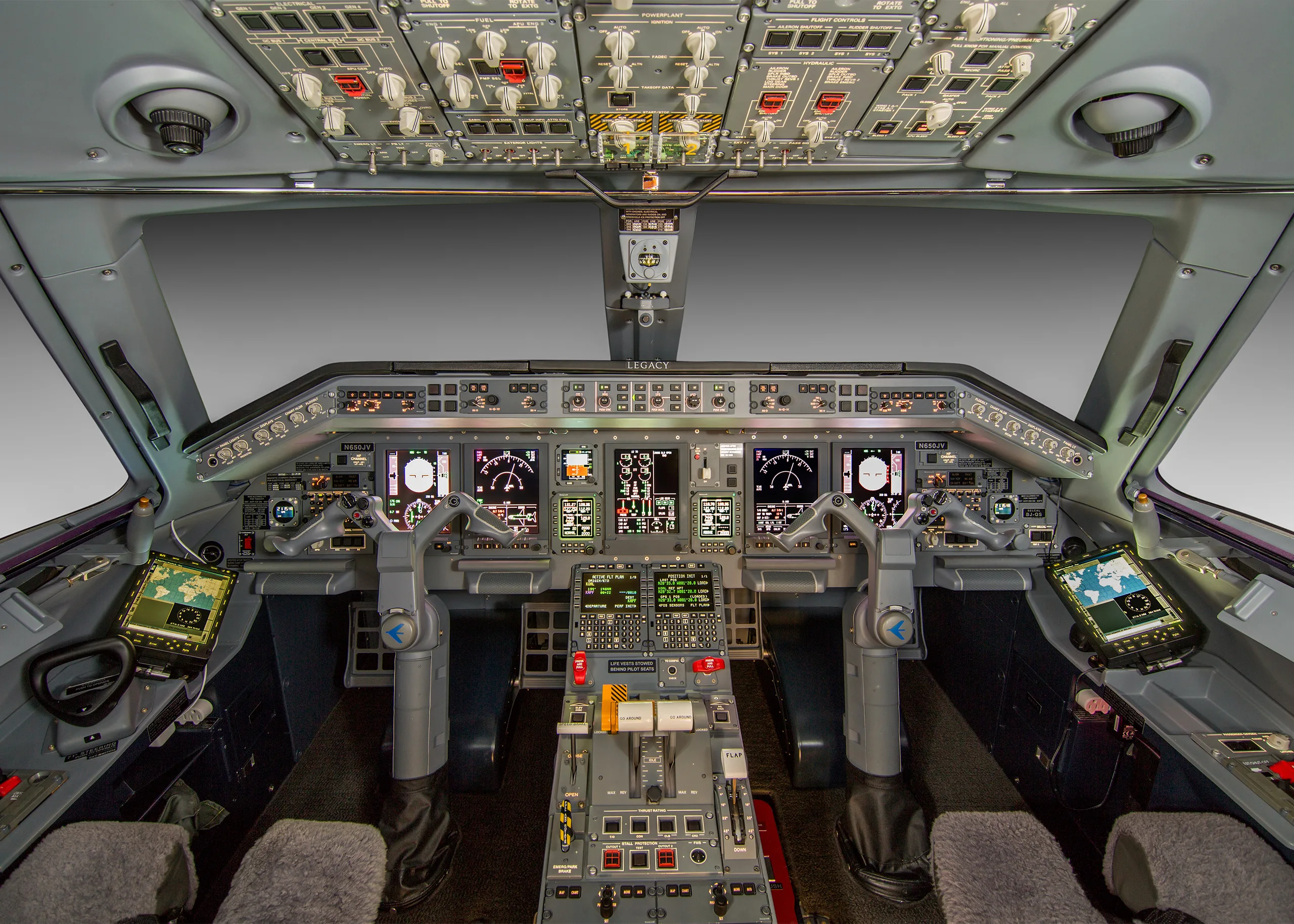 The detailed cockpit of an Embraer Legacy aircraft, featuring multiple display screens and numerous controls.