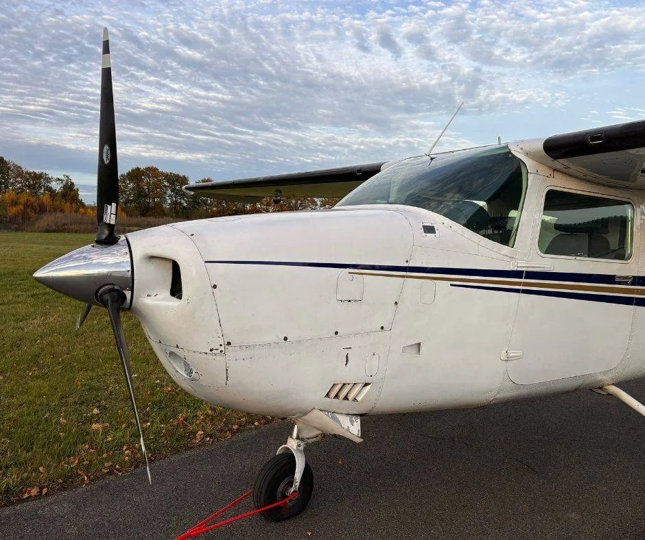 A close-up view of the front fuselage and propeller of the white Cessna 210 Centurion aircraft.