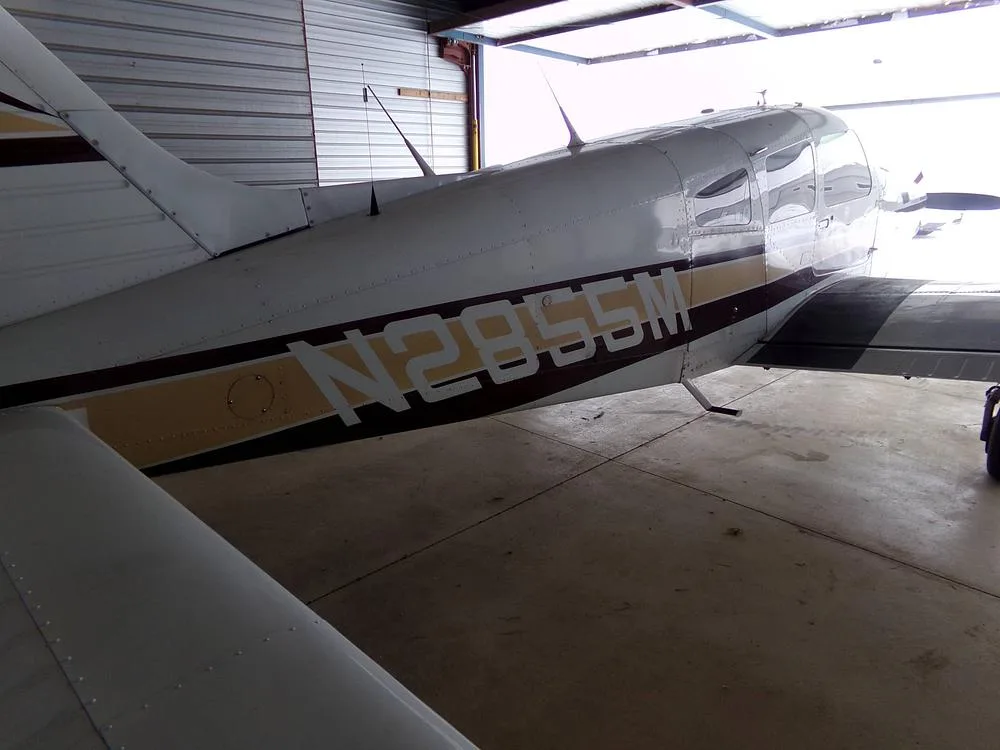 A close-up view of the rear fuselage of a white aircraft with brown and gold stripes, showing the registration N2855M.