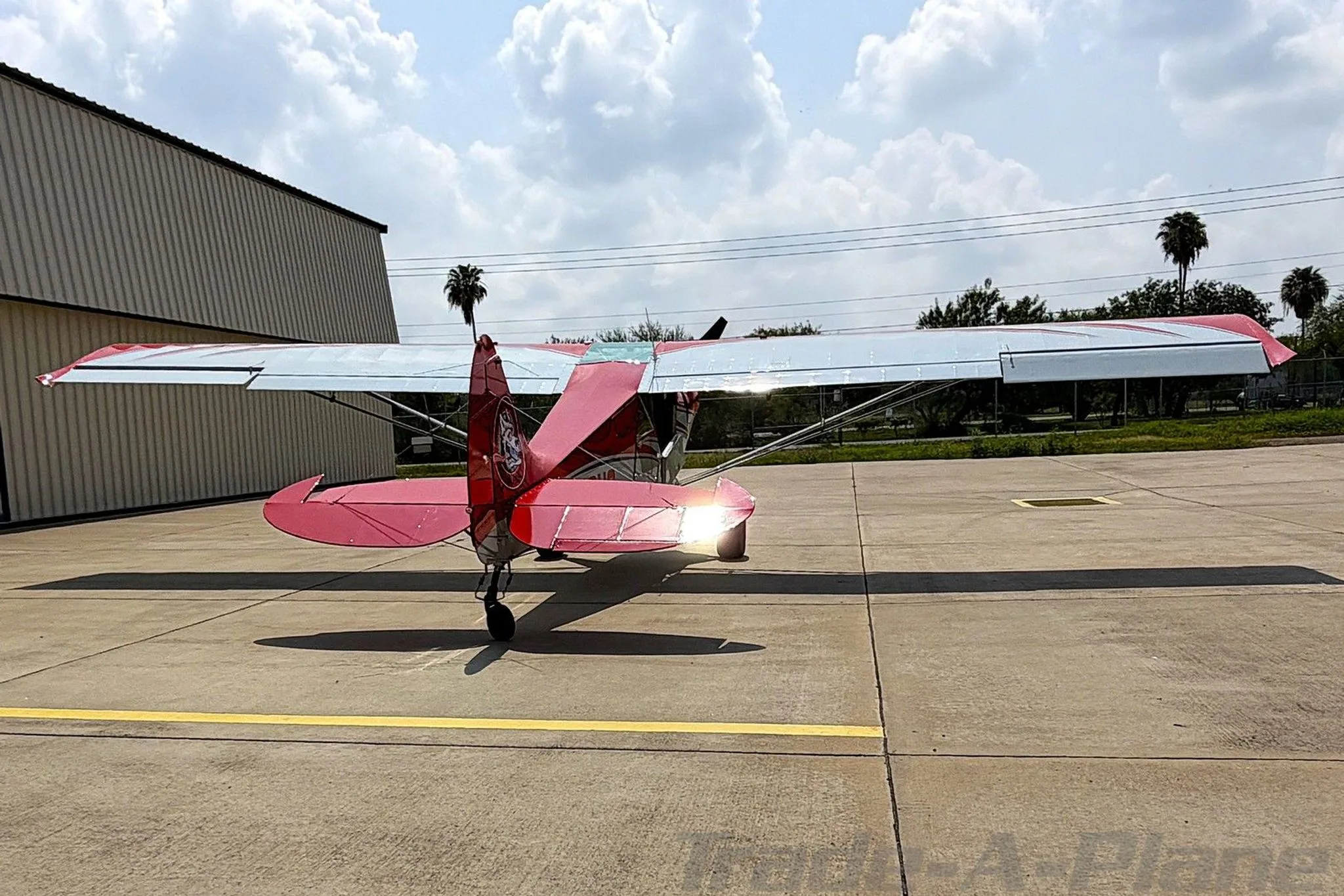 A rear view of the red and white Aviat Husky A-1C aircraft, registration N49HC, parked on an airfield.