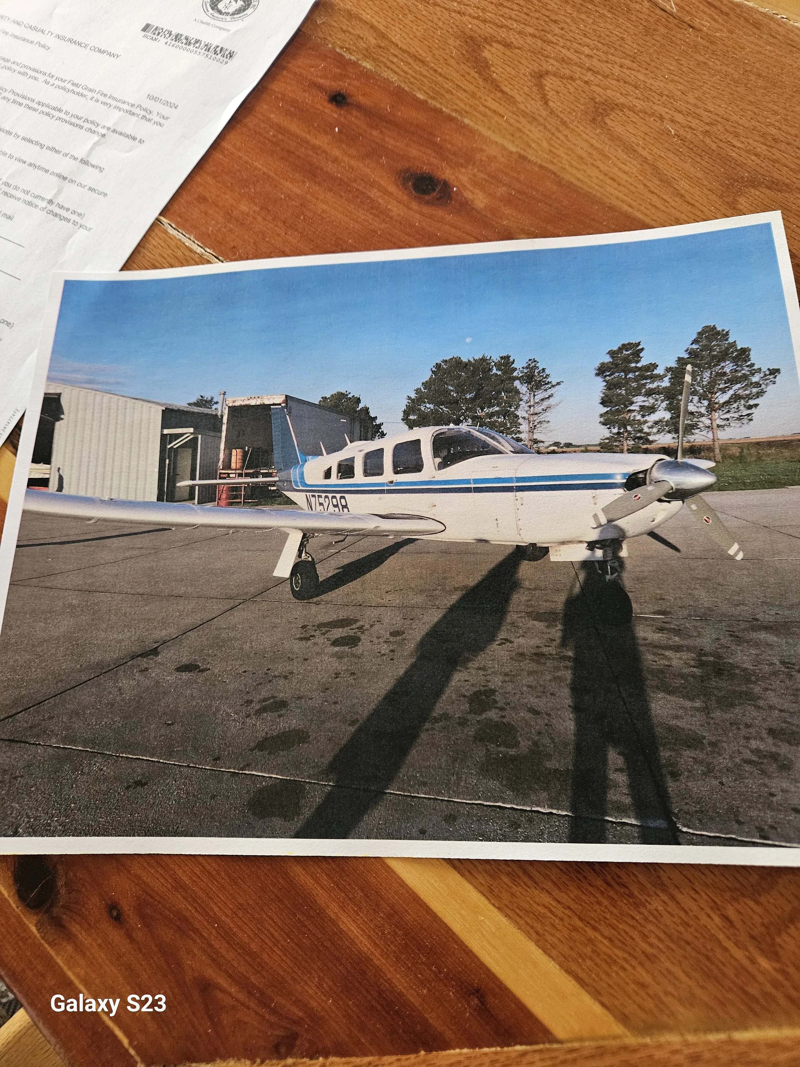 A white and blue Piper PA-32R-300 Lance (N75298) parked on an asphalt ramp with a hangar in the background.