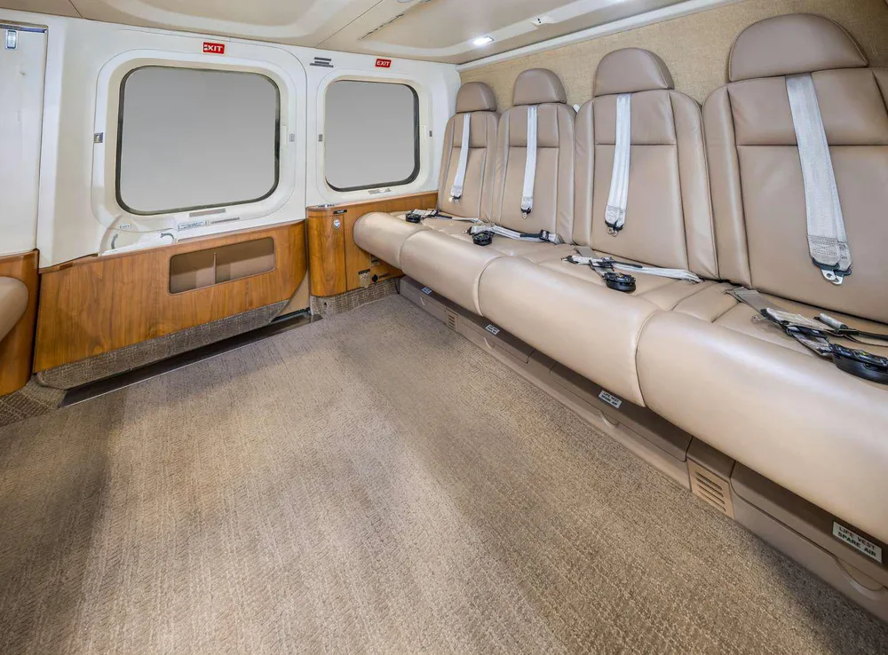 A wider view of the helicopter's interior cabin with tan leather seats and a beige carpet.