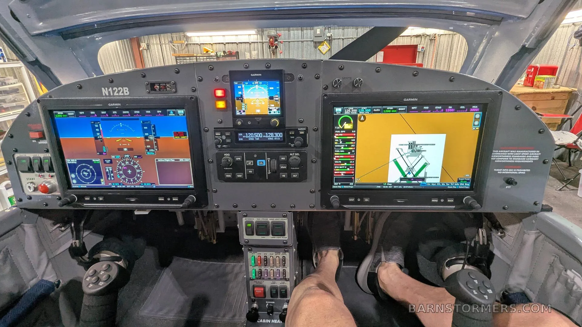 The cockpit of an aircraft, featuring a modern glass panel with multiple Garmin displays and flight controls.