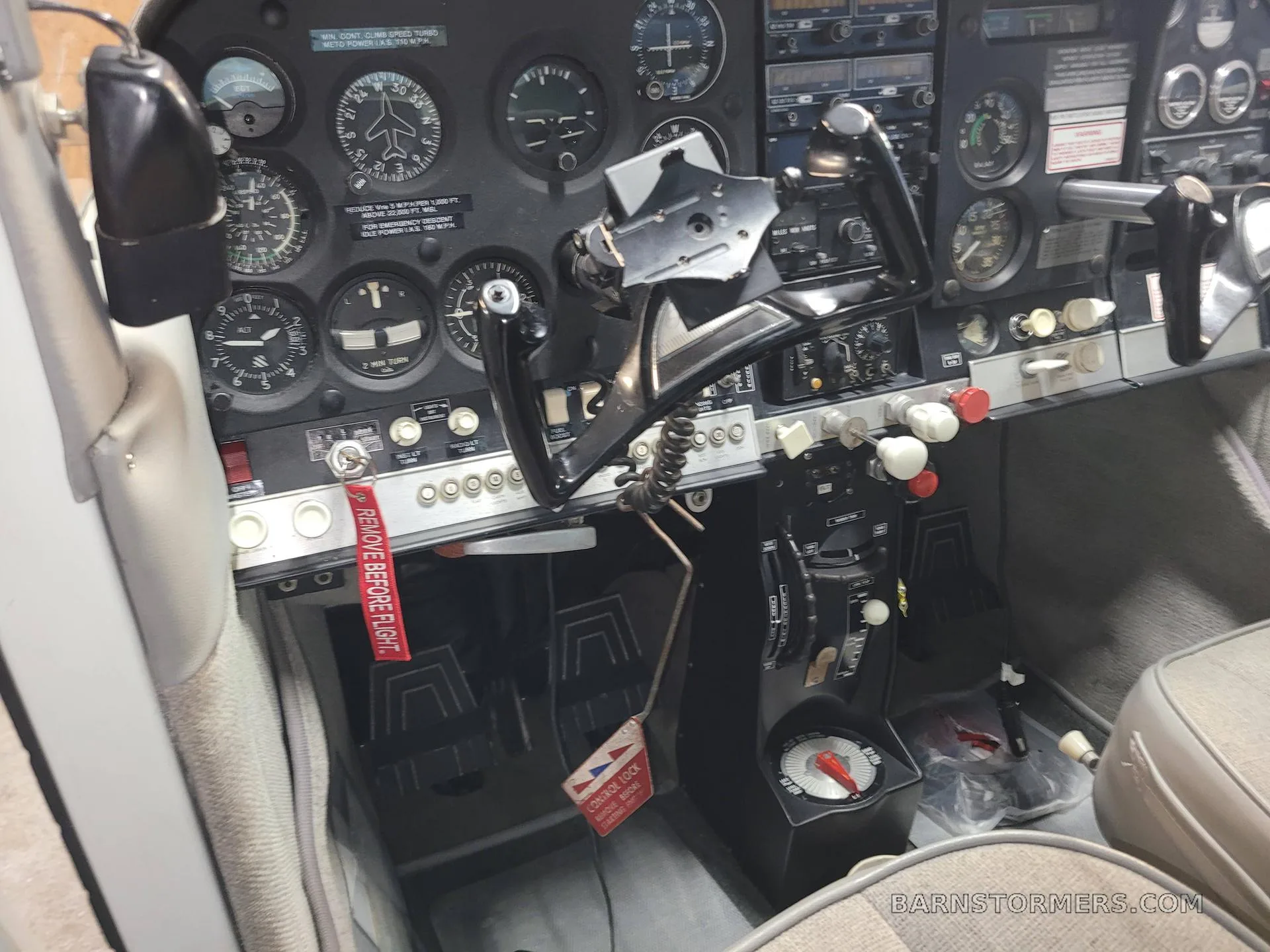 The cockpit of an aircraft, showing the instrument panel, yokes, and control levers.