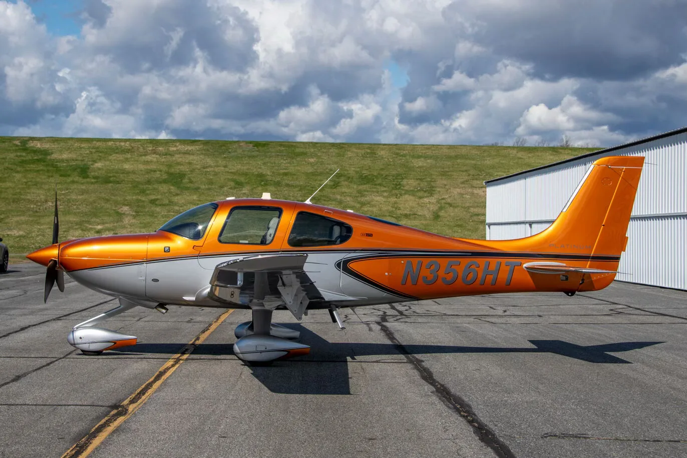 A side view of a metallic orange and silver Cirrus SR22 aircraft (N356HT) parked on an asphalt ramp.