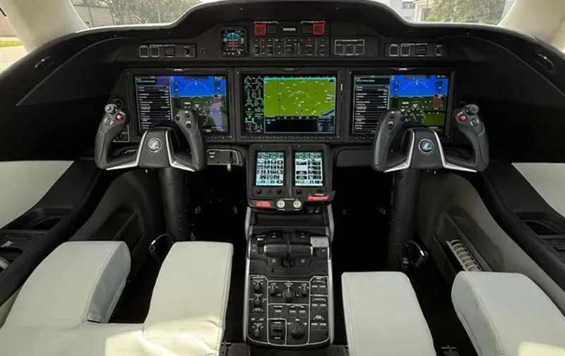 The cockpit of a HondaJet HA-420, featuring multiple large digital displays and a central control pedestal.