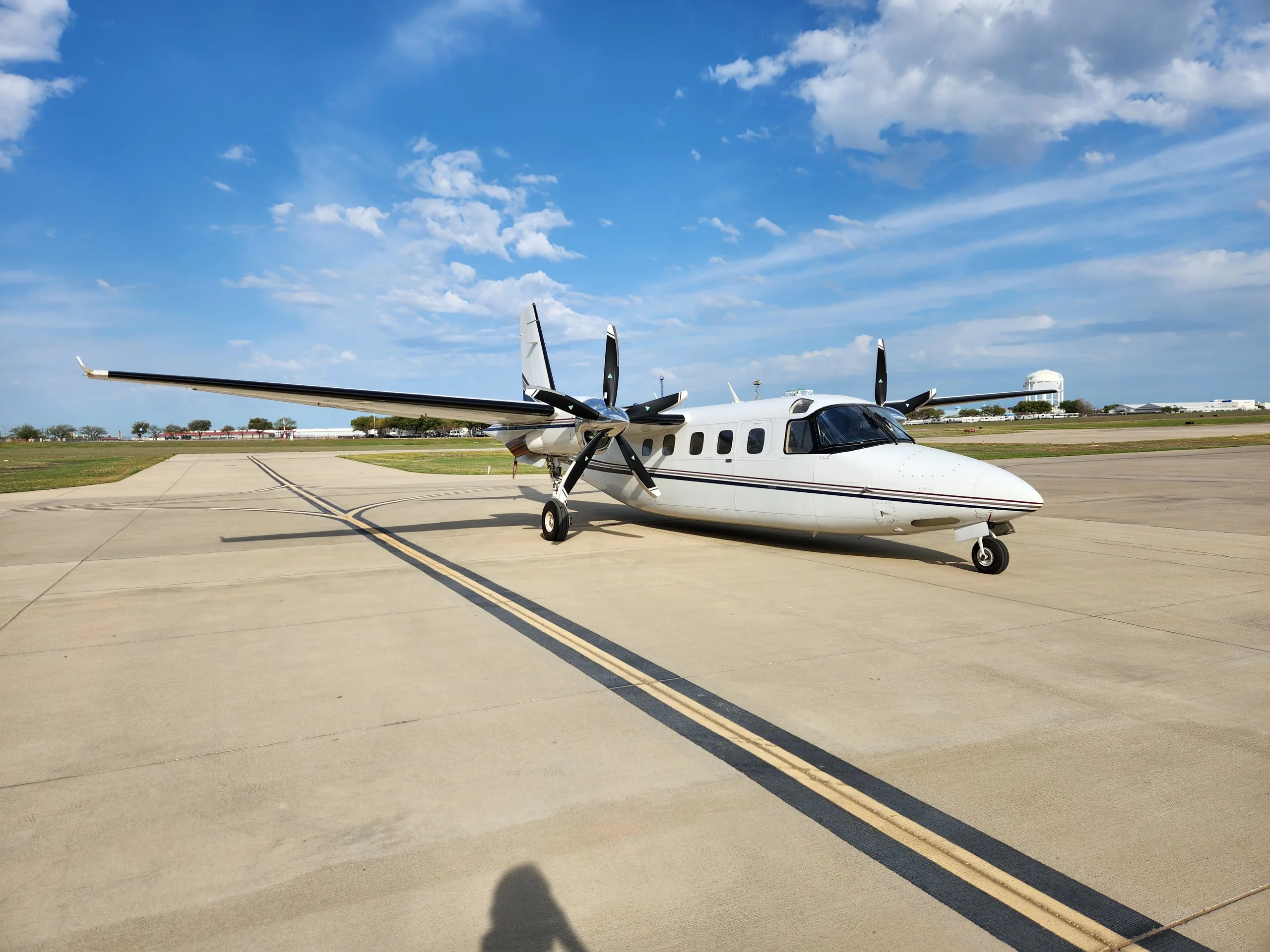 A white and black Commando aircraft is parked on the tarmac on a sunny day.