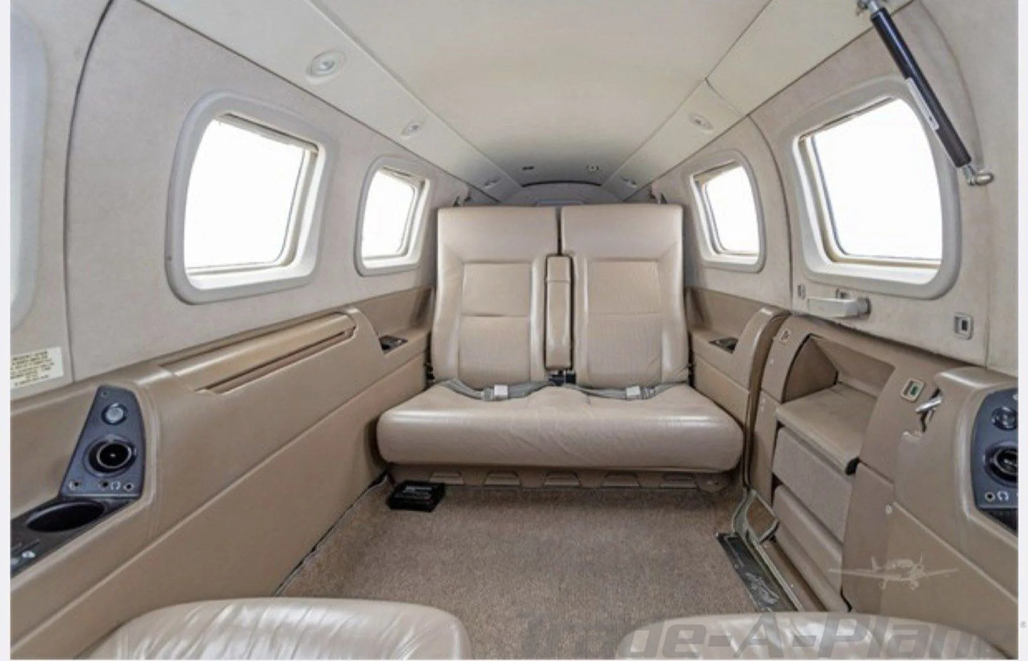 The aircraft cabin interior with two beige seats facing forward.