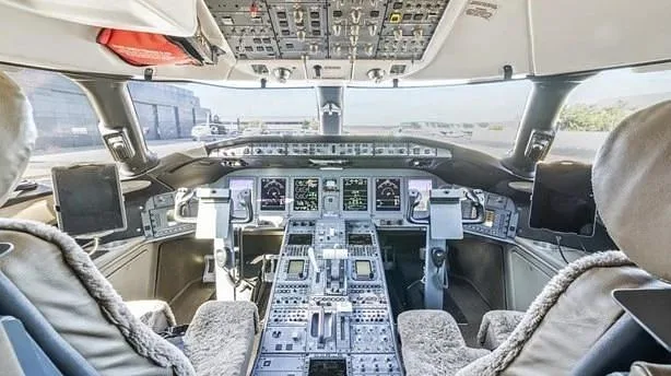 The spacious cockpit of a business jet features multiple digital displays and a complex control panel.
