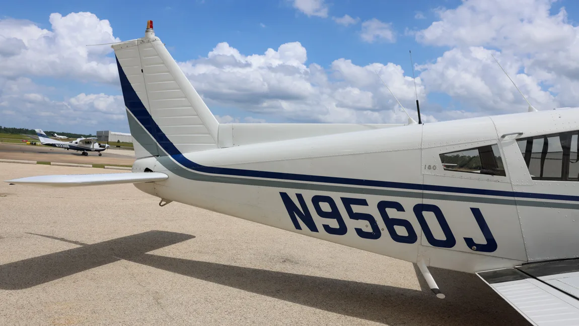 Close-up of the tail section of the Piper Cherokee 180 (N9560J) showing the vertical stabilizer and registration.