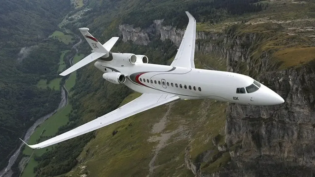 A Dassault Falcon 8X flying over a mountainous landscape.