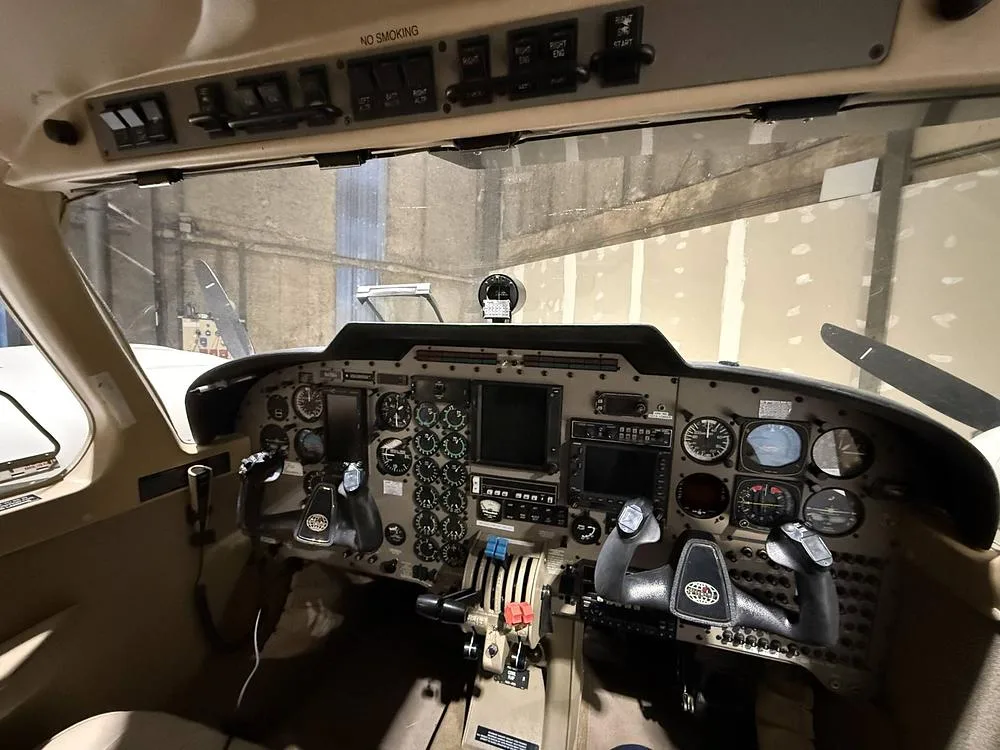 View from inside the cockpit showing the instrument panel, yokes, and overhead switches of the aircraft.