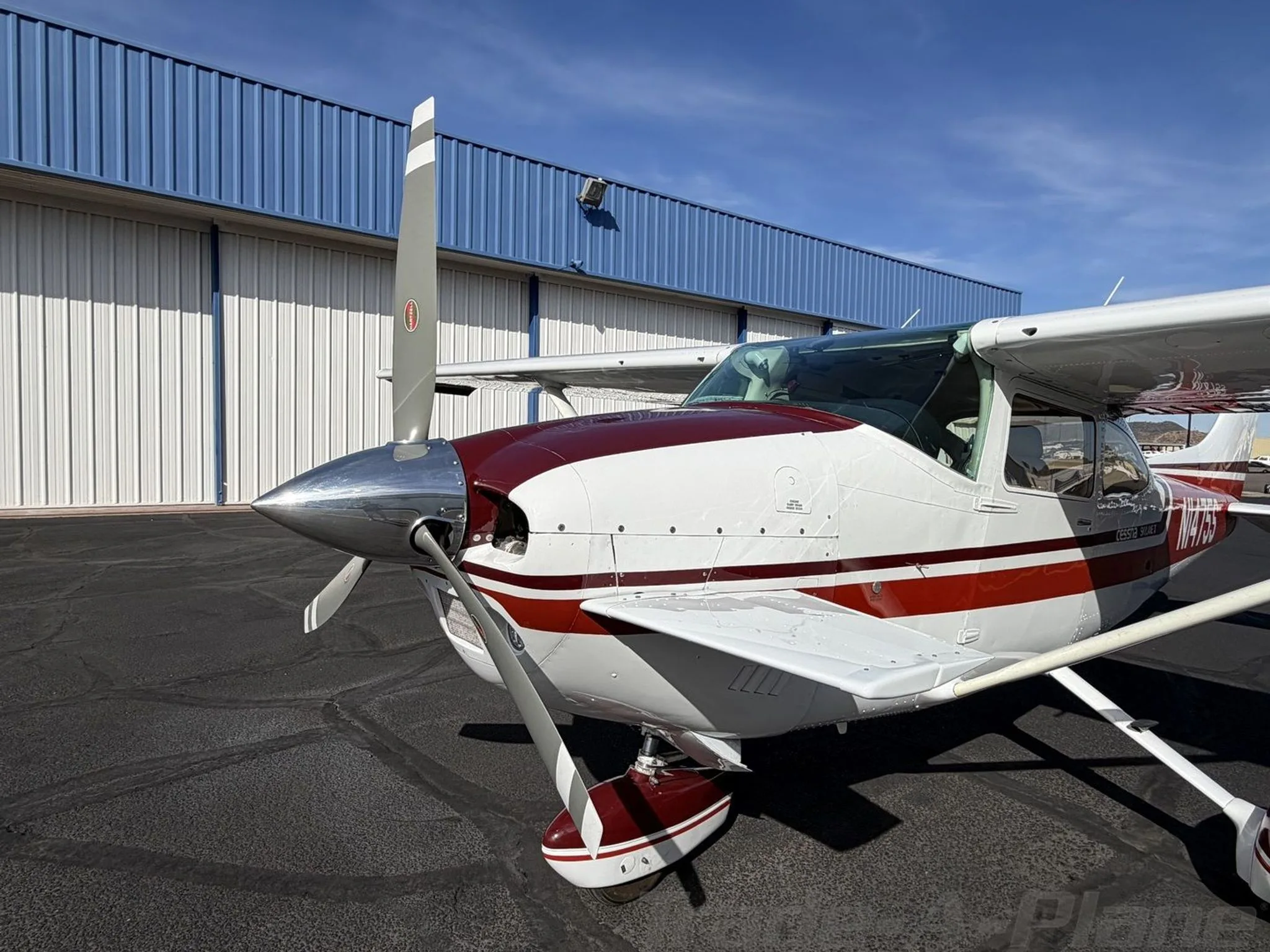 A close-up front-left view of the propeller and nose of the white and red Cessna Skylane II (N1475S).