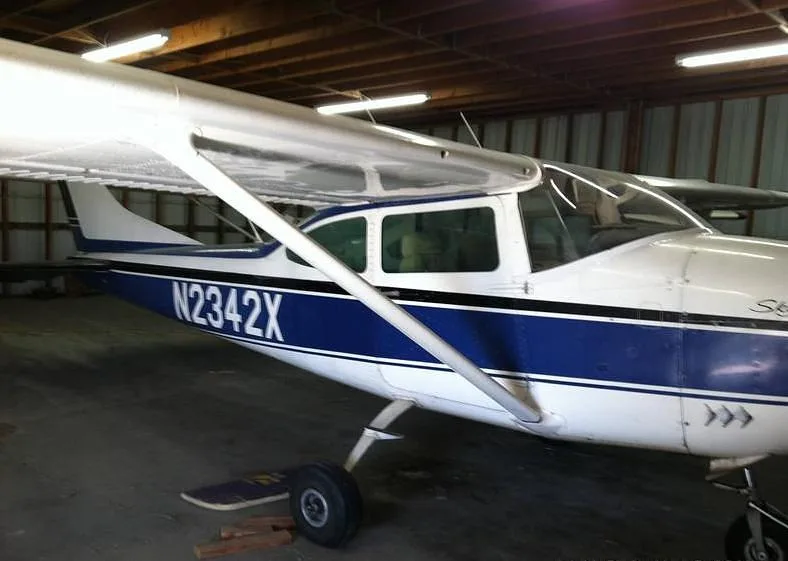 A white and blue Cessna Skylane N2342X parked inside a hangar.