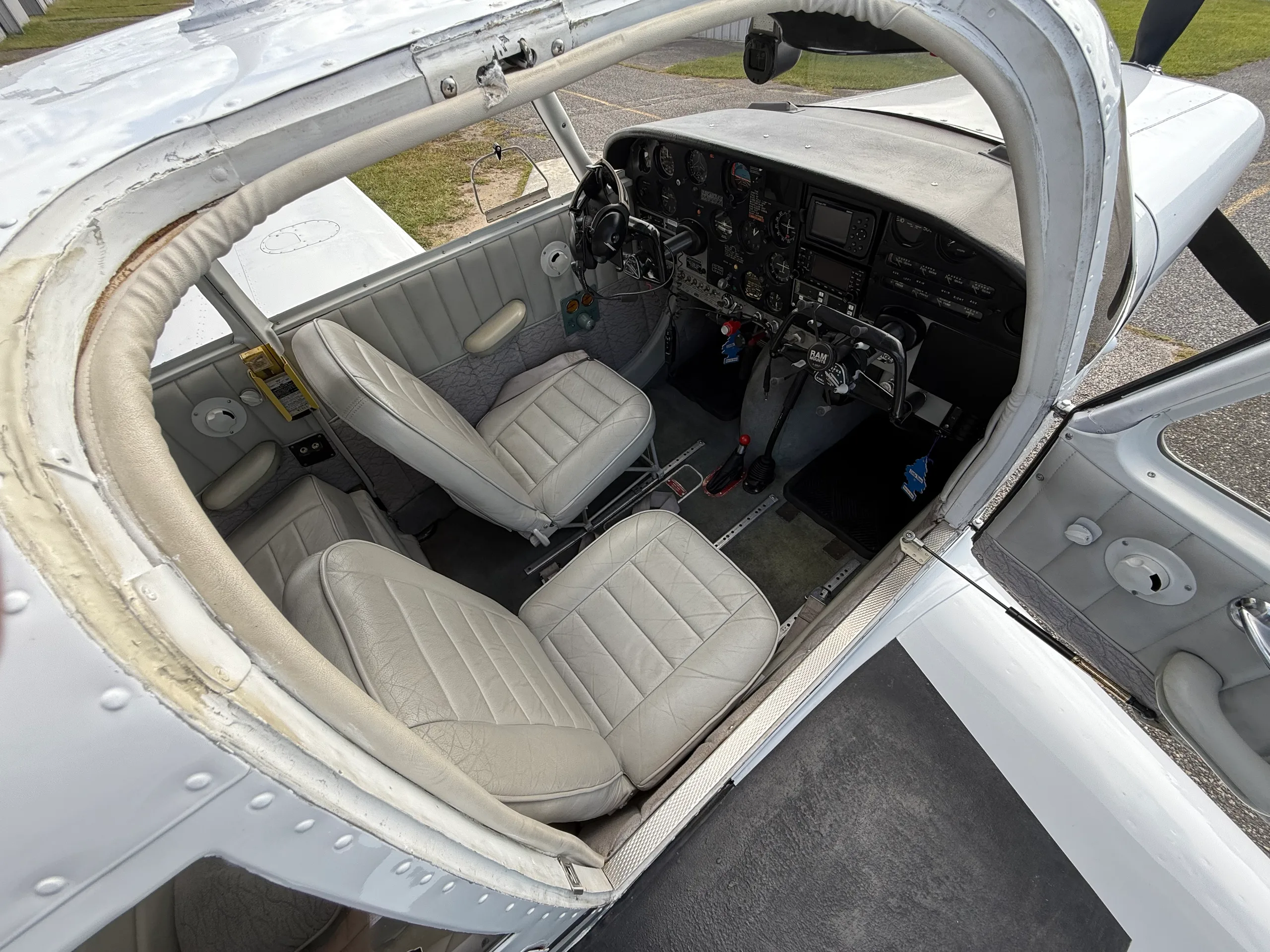 Overhead view looking into the cockpit of a small aircraft, showing the instrument panel and two light gray front seats.