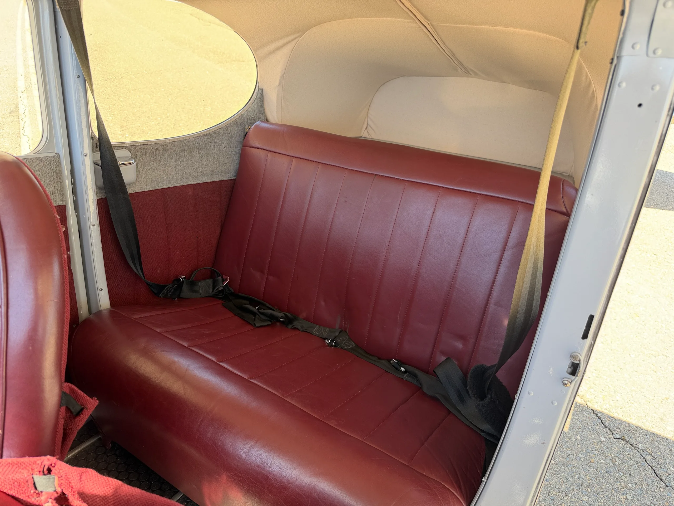 View of the red leather rear bench seat in the aircraft cabin.