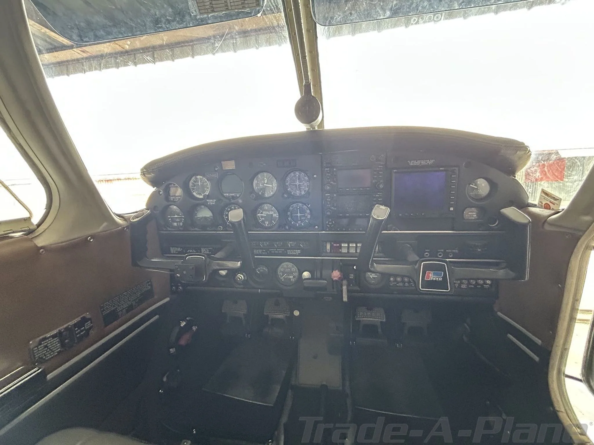 The cockpit instrument panel of a Piper aircraft, showing the dual yokes and a mix of analog and digital instruments.