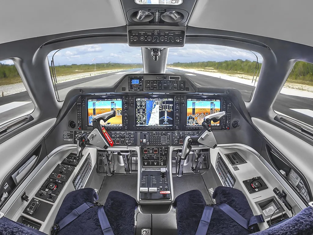 The modern cockpit features multiple large display screens and a clear view of a runway ahead.