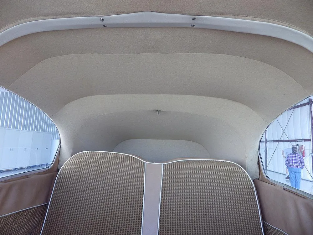 A view of the aircraft's rear cabin with tan upholstered seats and headliner.