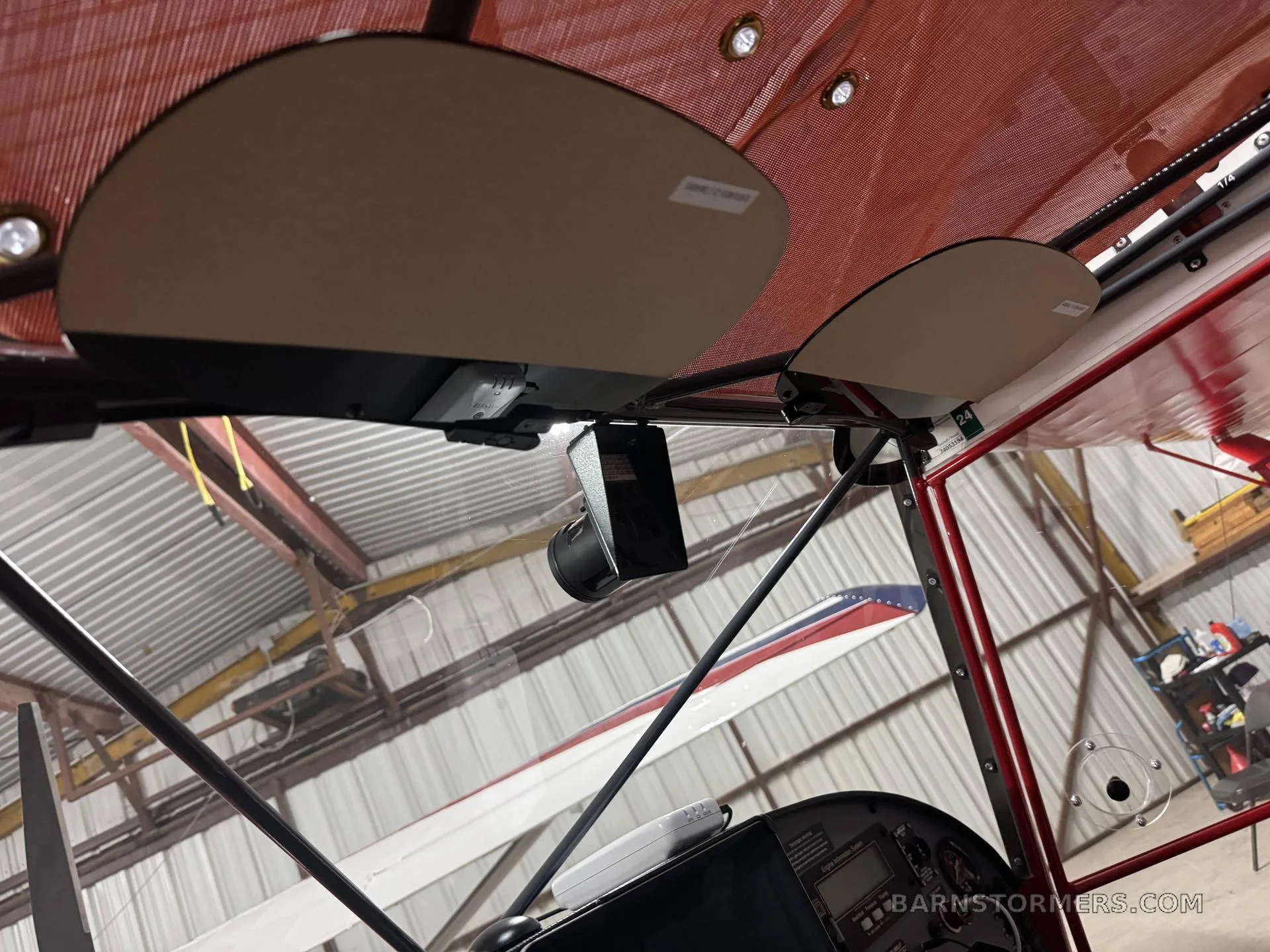 An interior view of an aircraft cabin, showing sun visors and the ceiling, with another aircraft visible in the background.