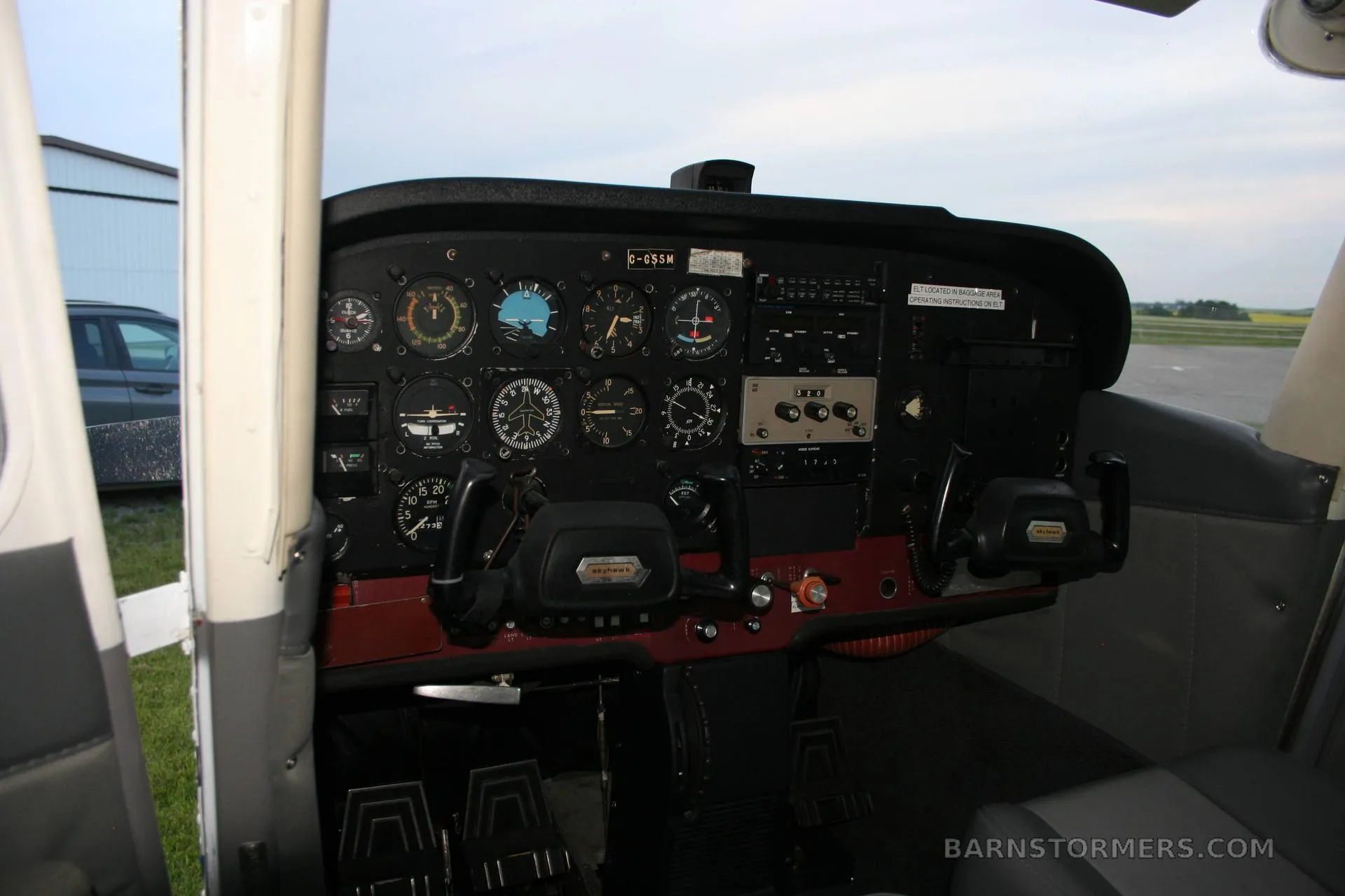 The black instrument panel and yokes of a Cessna 172 cockpit are visible, with various gauges and controls.