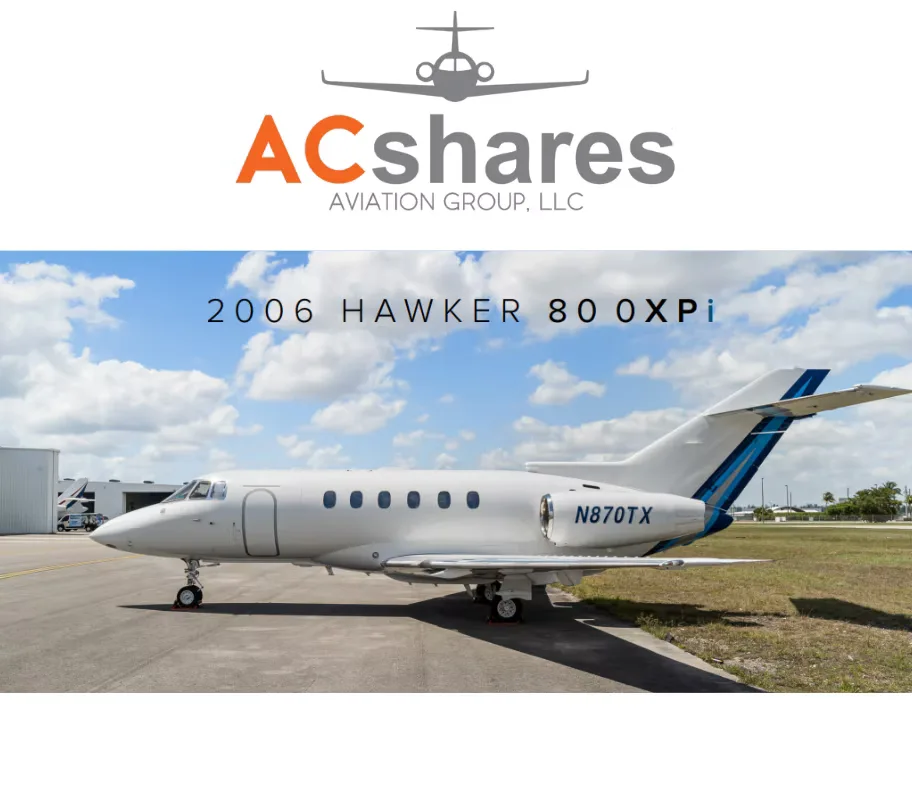 A white Hawker 800XPi business jet with blue tail stripes is parked on an airport tarmac under a partly cloudy sky.