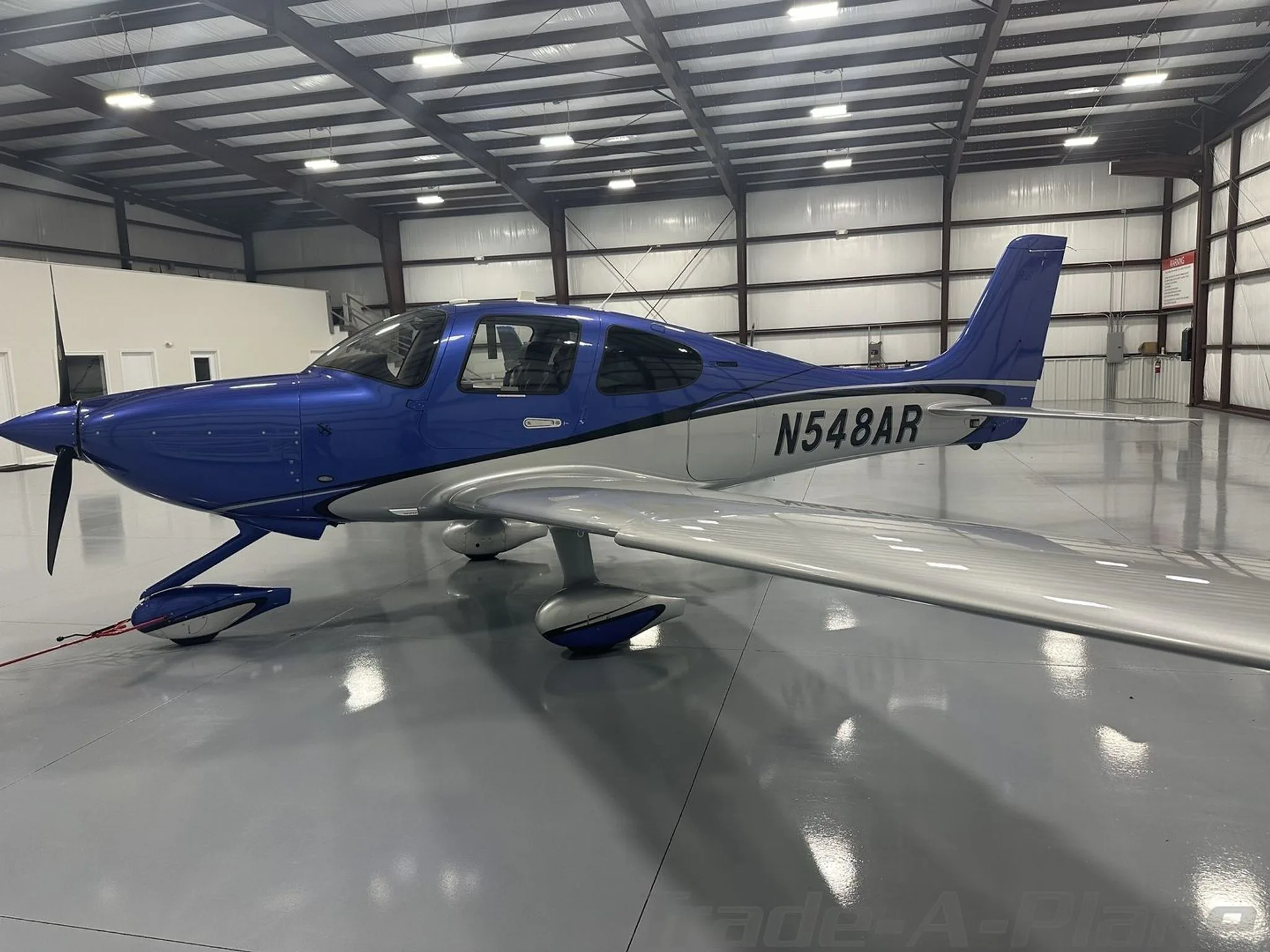A side view of the blue and silver Cirrus SR22 aircraft N548AR in a hangar.