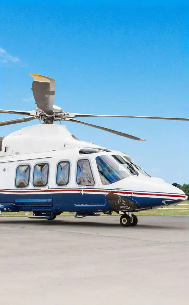 A close-up side view of the front section of a white and blue helicopter on a tarmac.