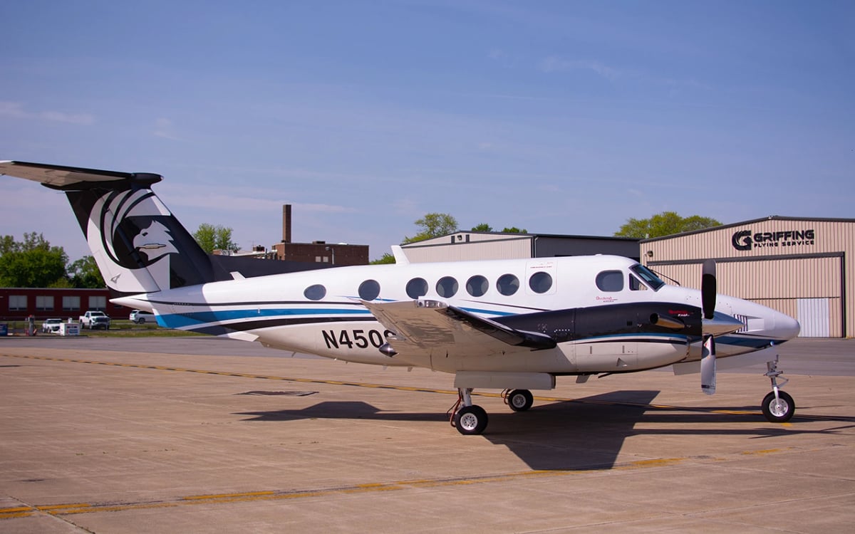Side view of a white and black turboprop with blue accents, tail number N450S.
