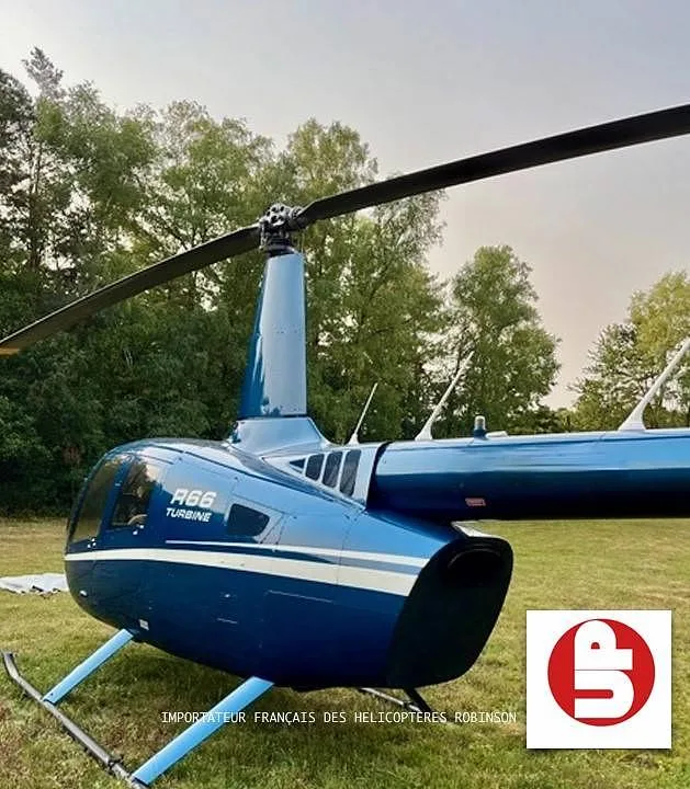 A close-up view of the blue Robinson R66 Turbine helicopter's fuselage and main rotor.