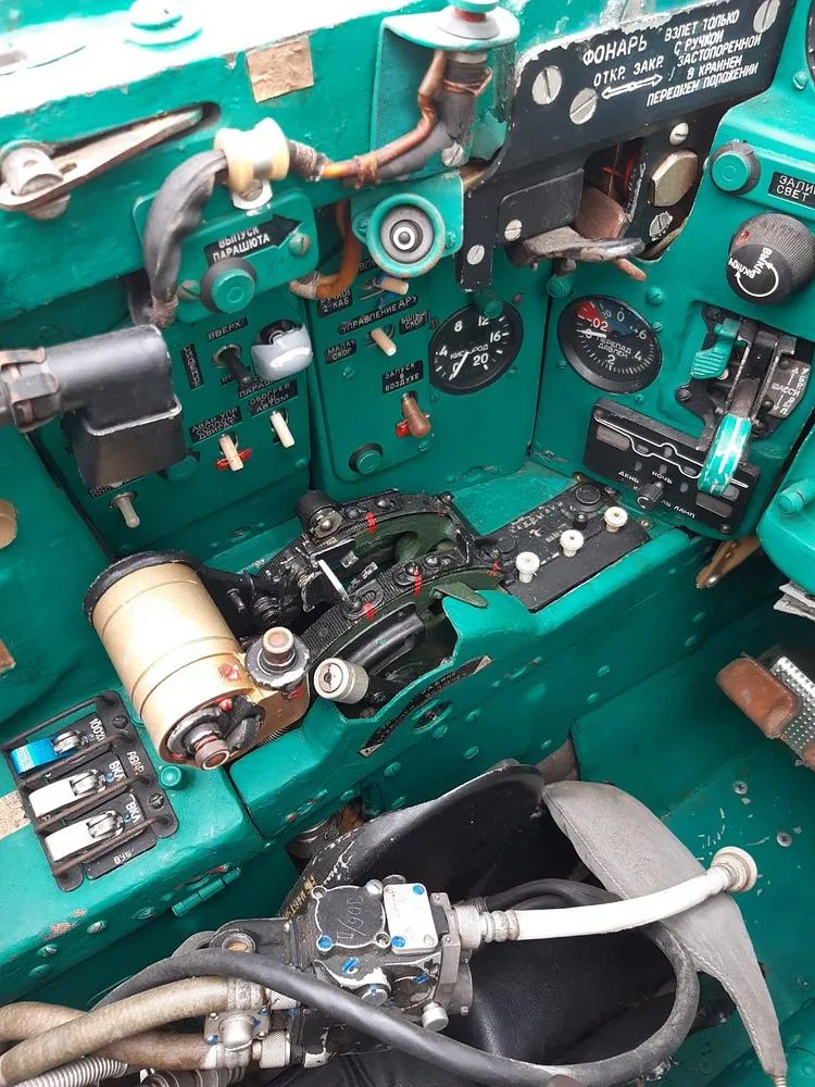 A close-up view of the green-painted instrument panel and controls inside a fighter jet cockpit.