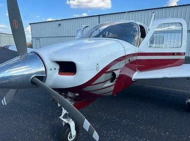 A close-up front view of the white and red aircraft N1292J, highlighting its propeller and open door.