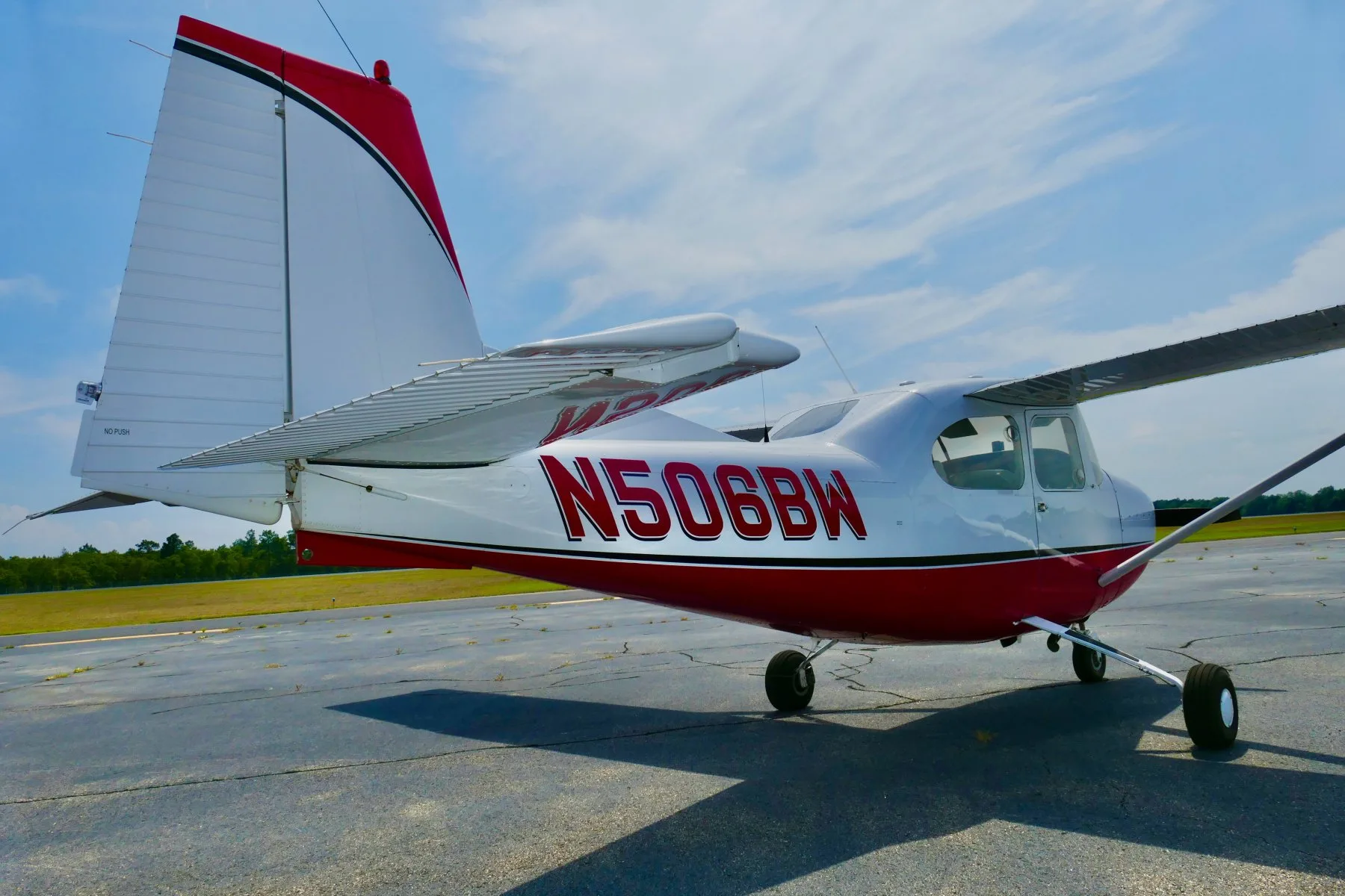 A rear-right view of a white and red Cessna 172 aircraft, N506BW, highlighting the tail section.